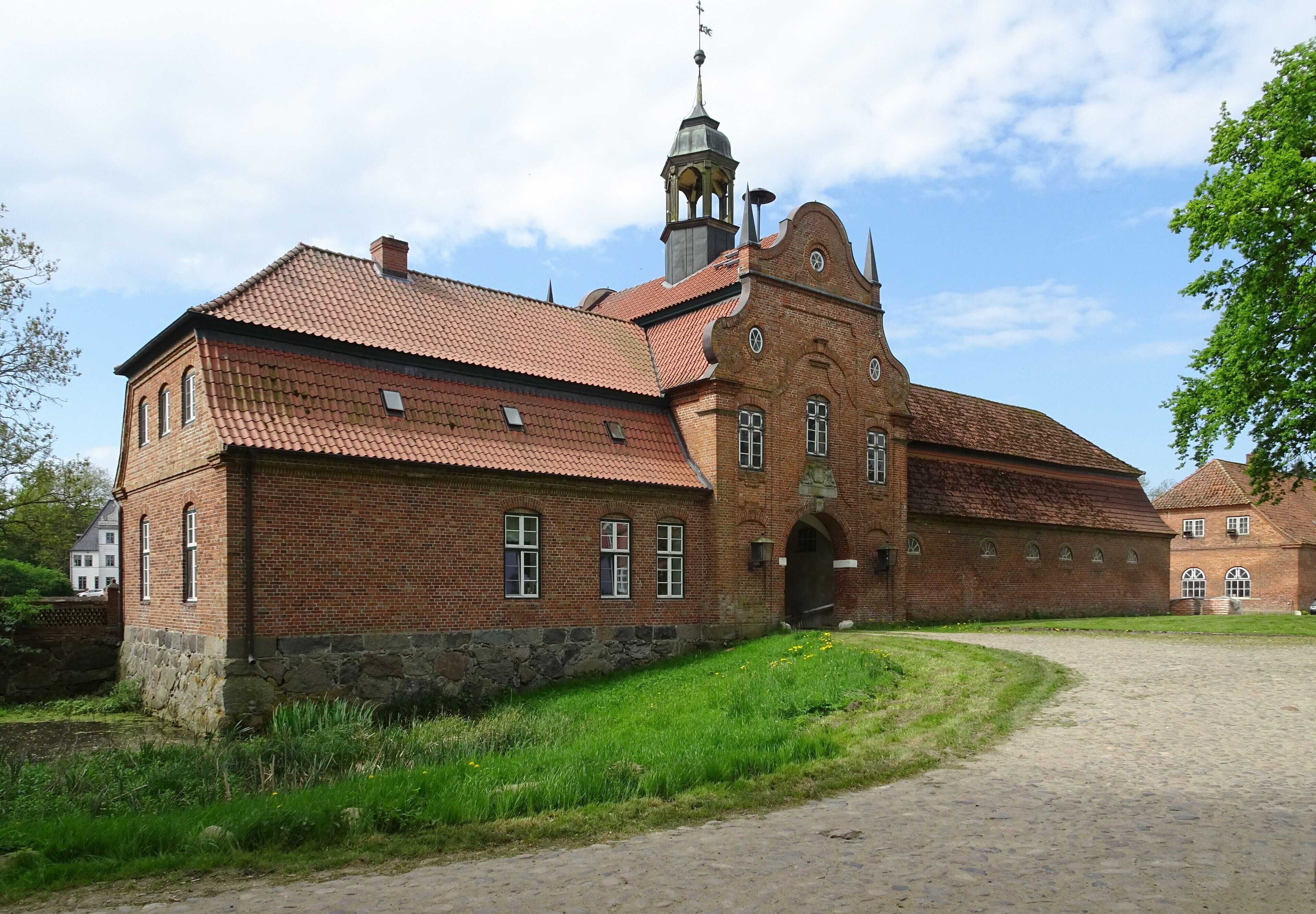 A historic brick building with a red-tiled roof and a bell tower.