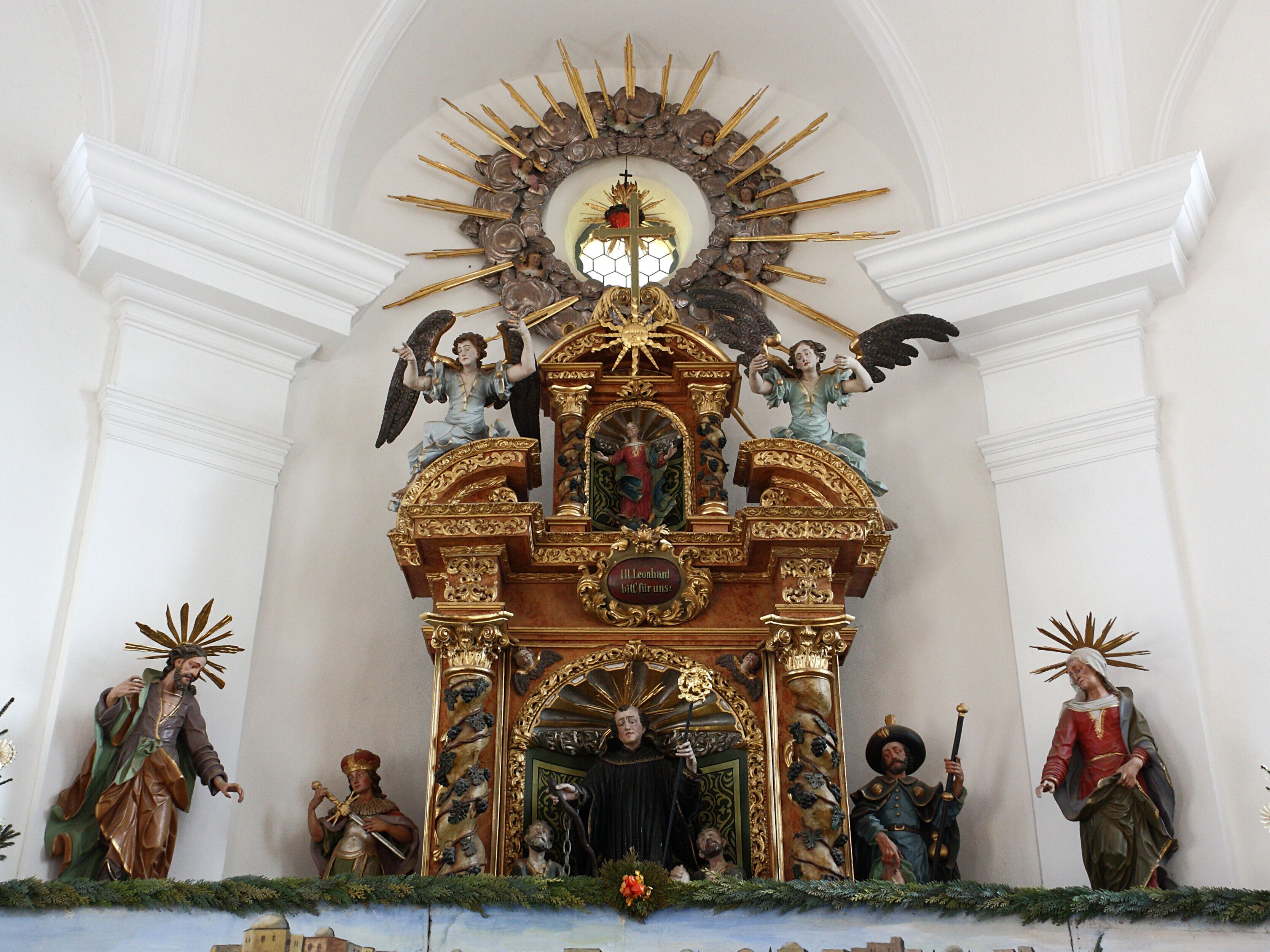 Kapelle St. Leonhard, Balzhausen; vom Krippenaufbau teilweise verdeckter Altar mit den Figuren des hl. Leonhard, flankiert von den Hll. Chlodwig (links, seinem Vater), und Rochus. Außen die Figuren der Eltern Marias, Joachim und Anna. In der Nische des Segmentgiebels Figur der Immaculata, beidseits davon sitzende Engel.