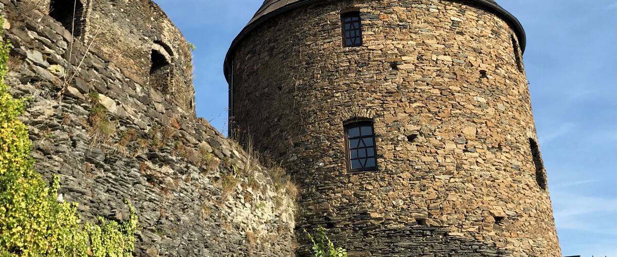 A stone tower with a conical roof and a smaller adjacent tower with arched openings.