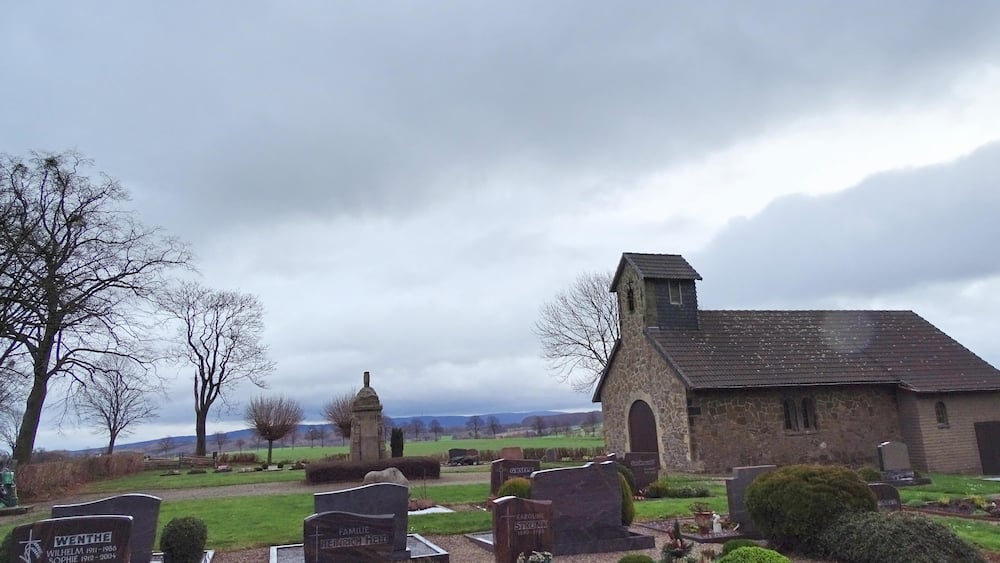 A cemetery with stone headstones and a small church.