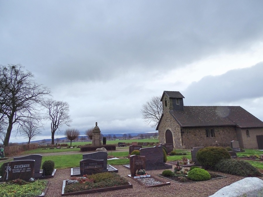 A cemetery with stone headstones and a small church.