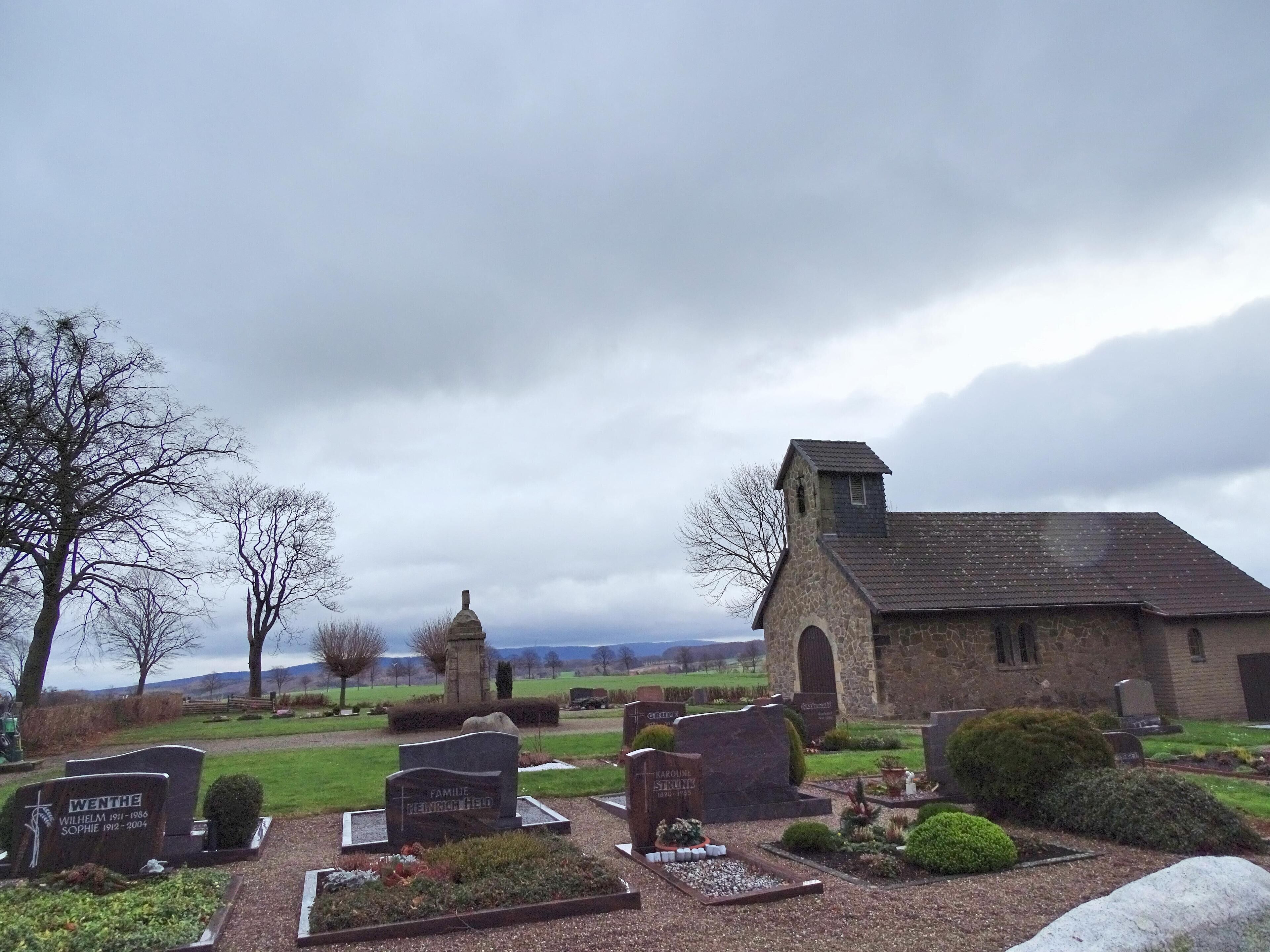 A cemetery with stone headstones and a small church.