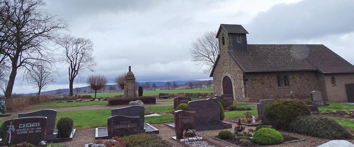 A cemetery with stone headstones and a small church.