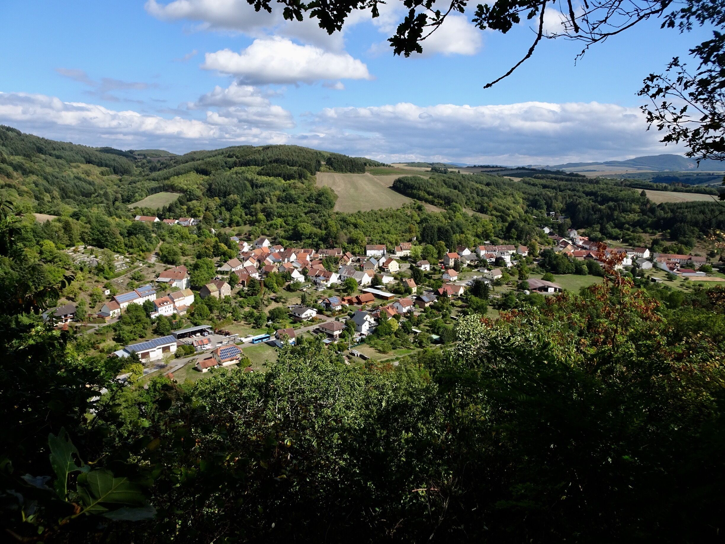 A village nestled in a valley surrounded by hills and forests.