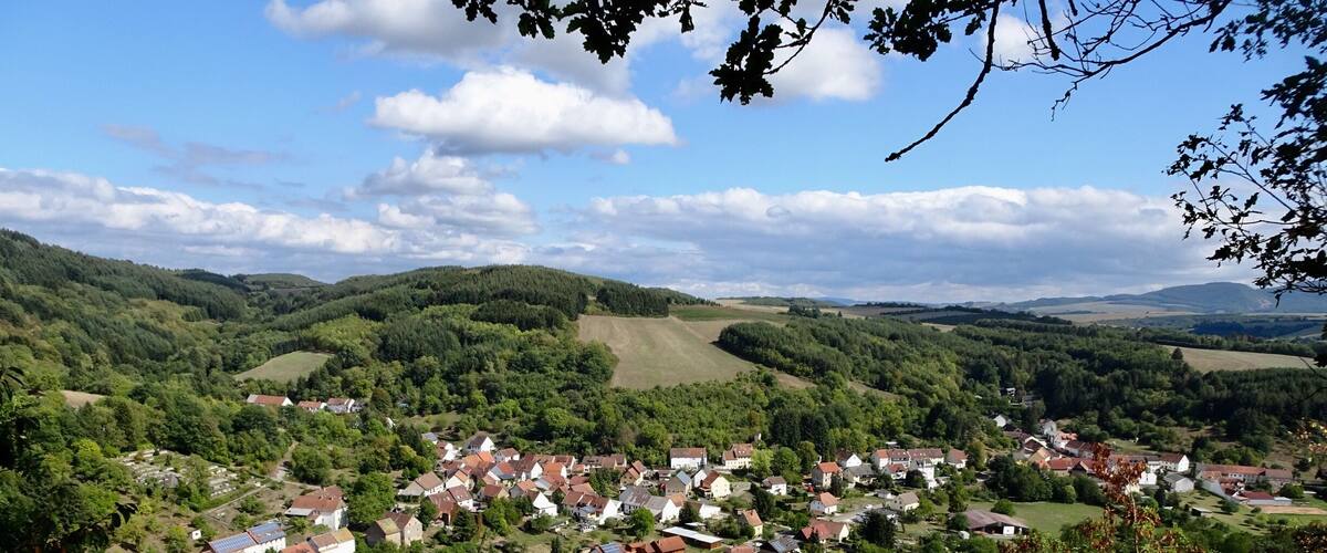 A village nestled in a valley surrounded by hills and forests.