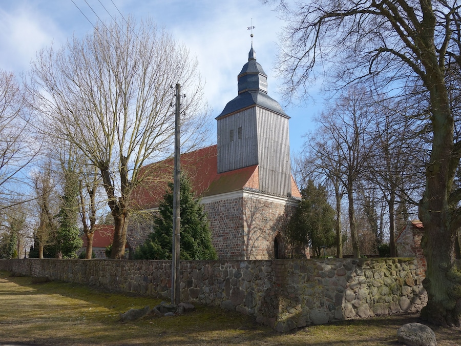 Una iglesia con una torre de piedra y un tejado rojo.