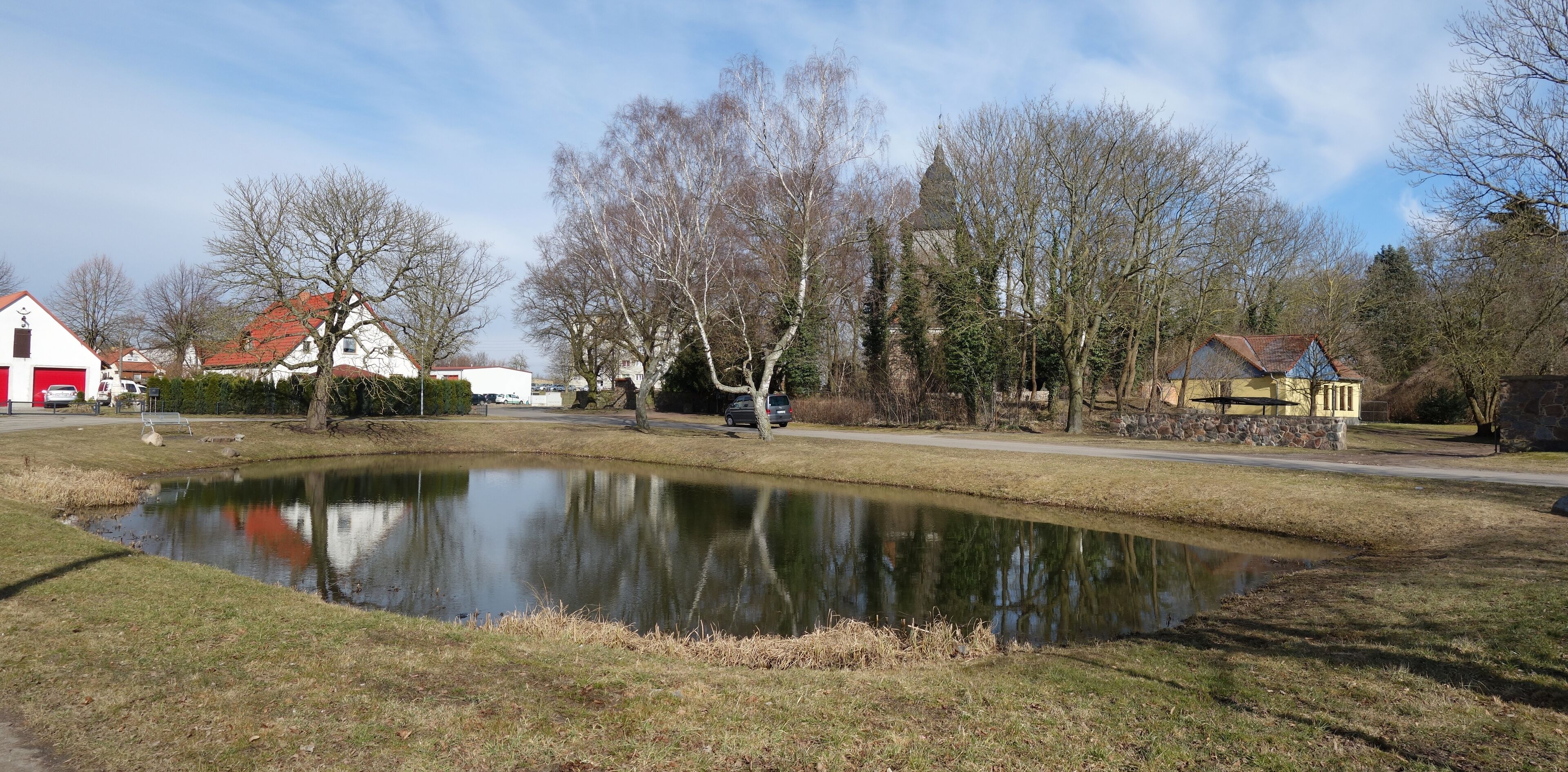 A pond surrounded by trees and houses.