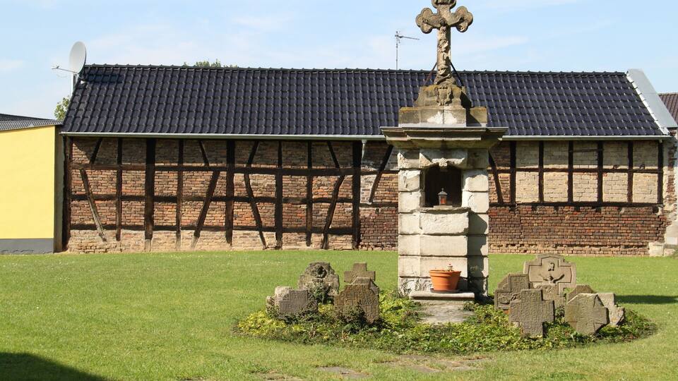 A cemetery with stone headstones and a stone monument with a cross.