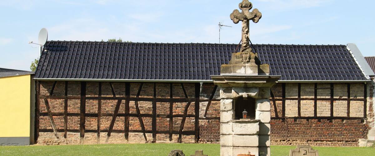 A cemetery with stone headstones and a stone monument with a cross.