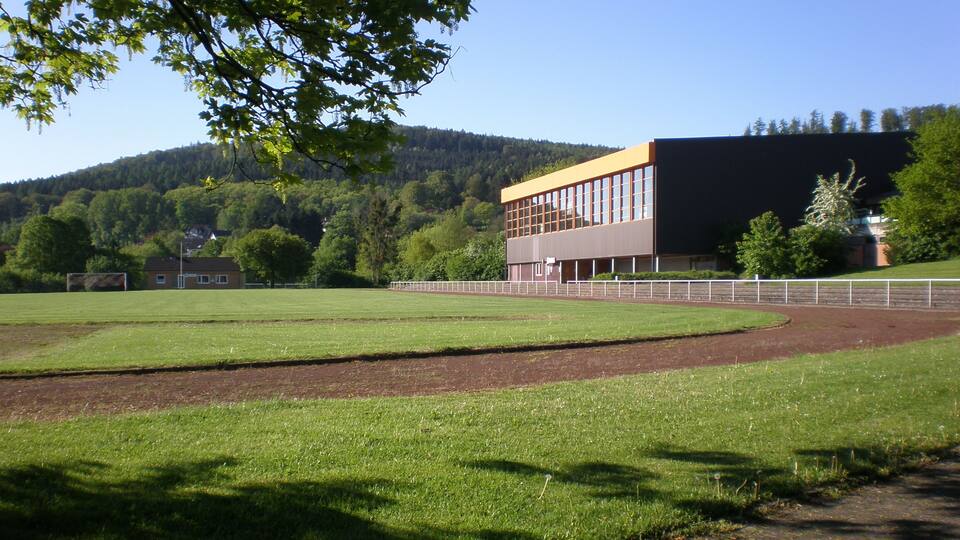 A baseball field with a modern building in the background.