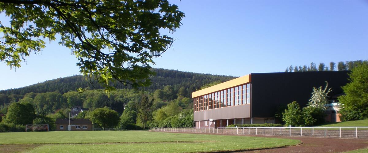 A baseball field with a modern building in the background.