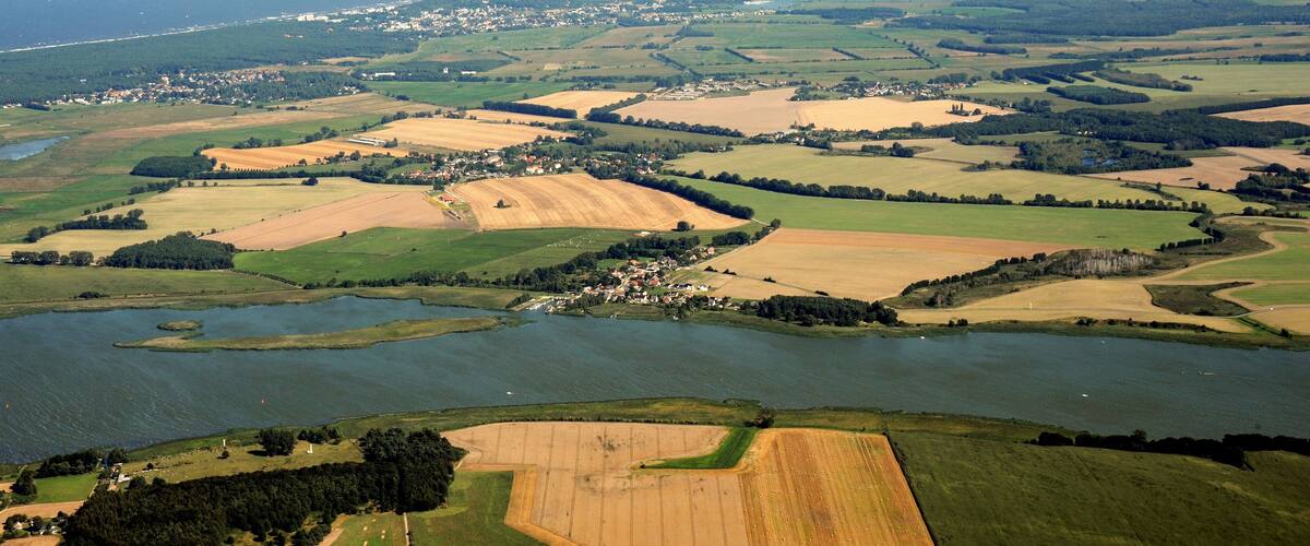 A coastal landscape with fields, a small town, and a body of water.