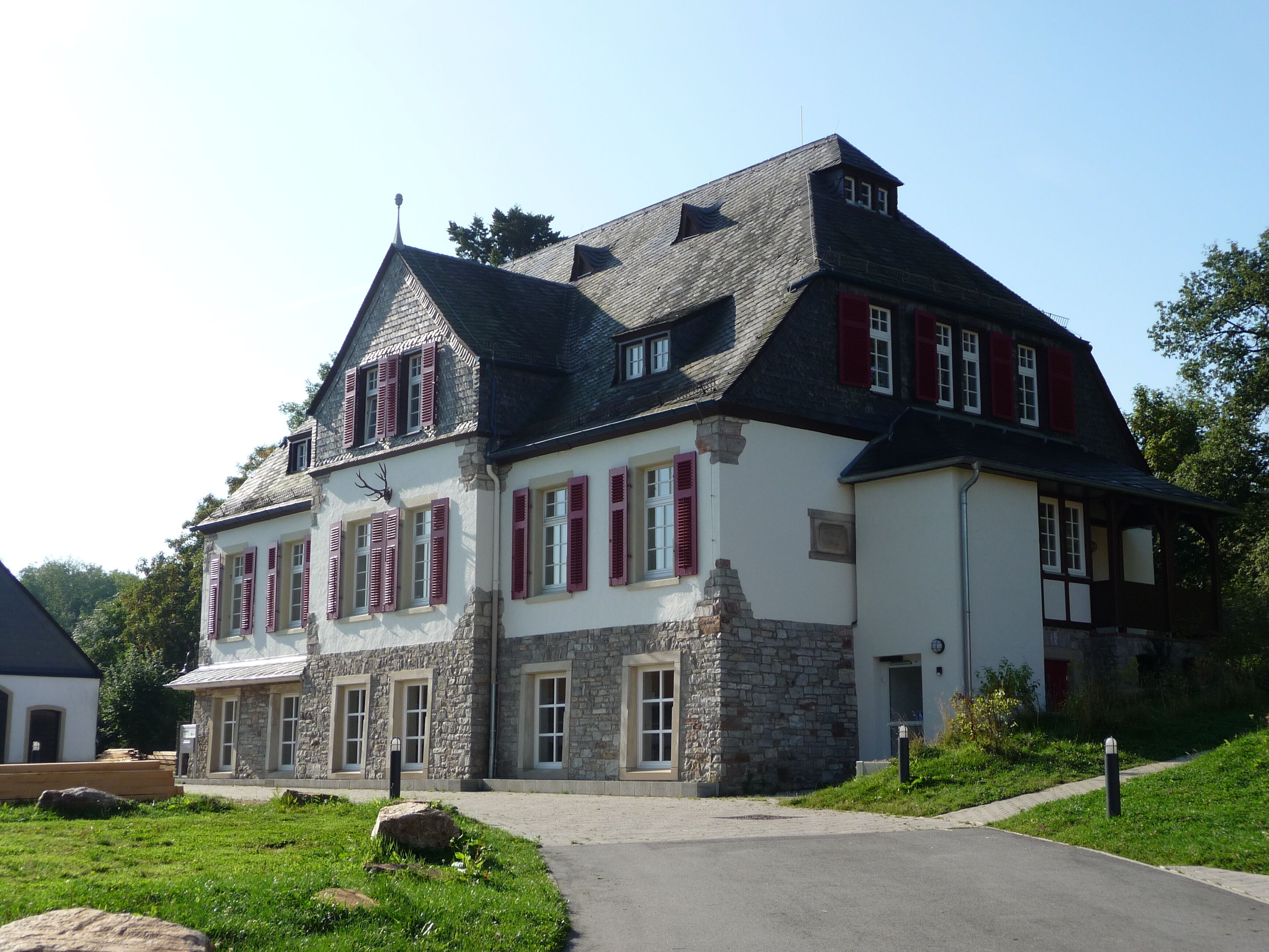 A large stone building with red shutters and a steep roof.
