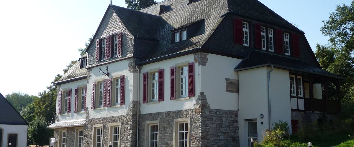 A large stone building with red shutters and a steep roof.