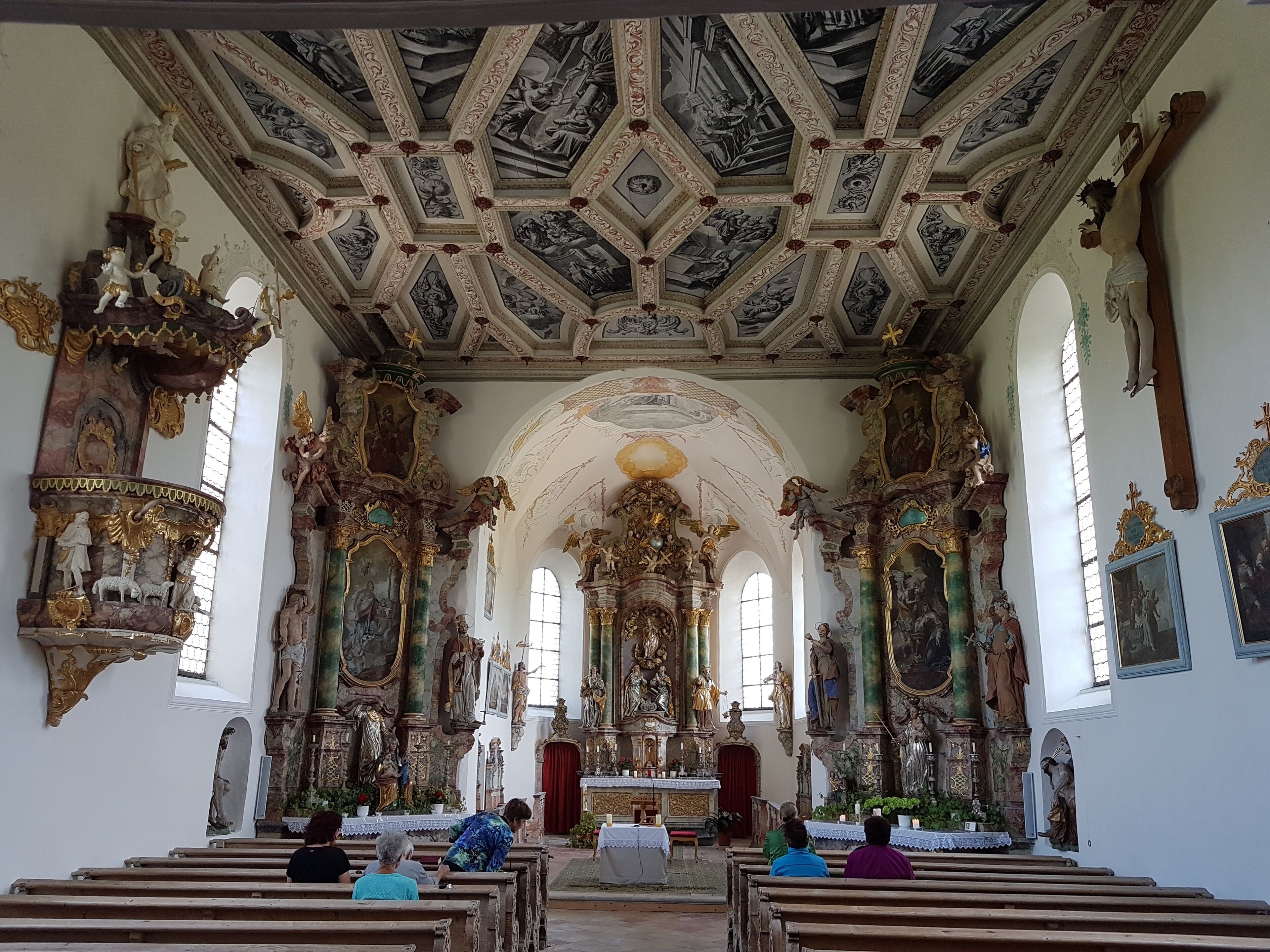 An ornate church interior with detailed frescoes, statues, and a high ceiling.