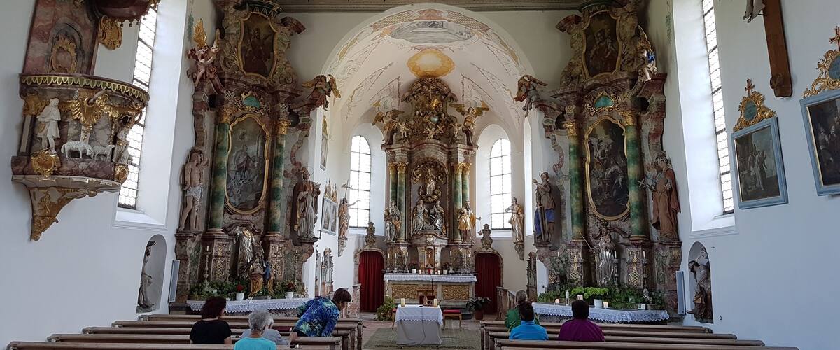 An ornate church interior with detailed frescoes, statues, and a high ceiling.