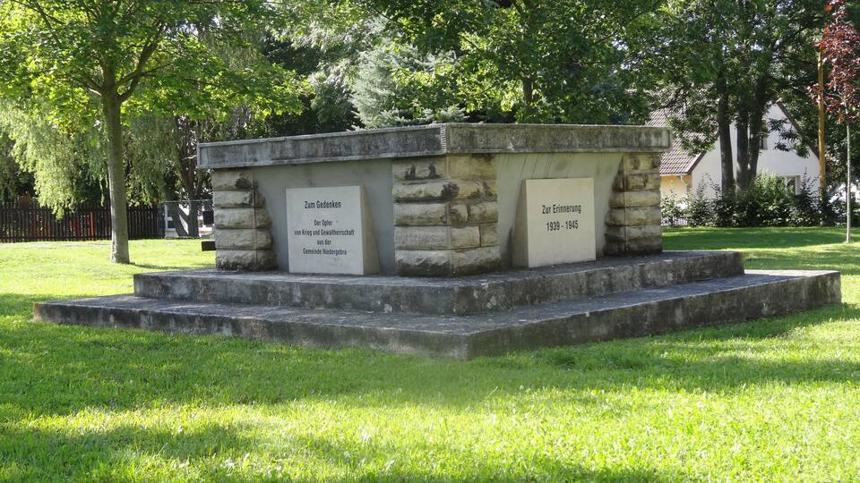 A stone monument with inscriptions in a park.