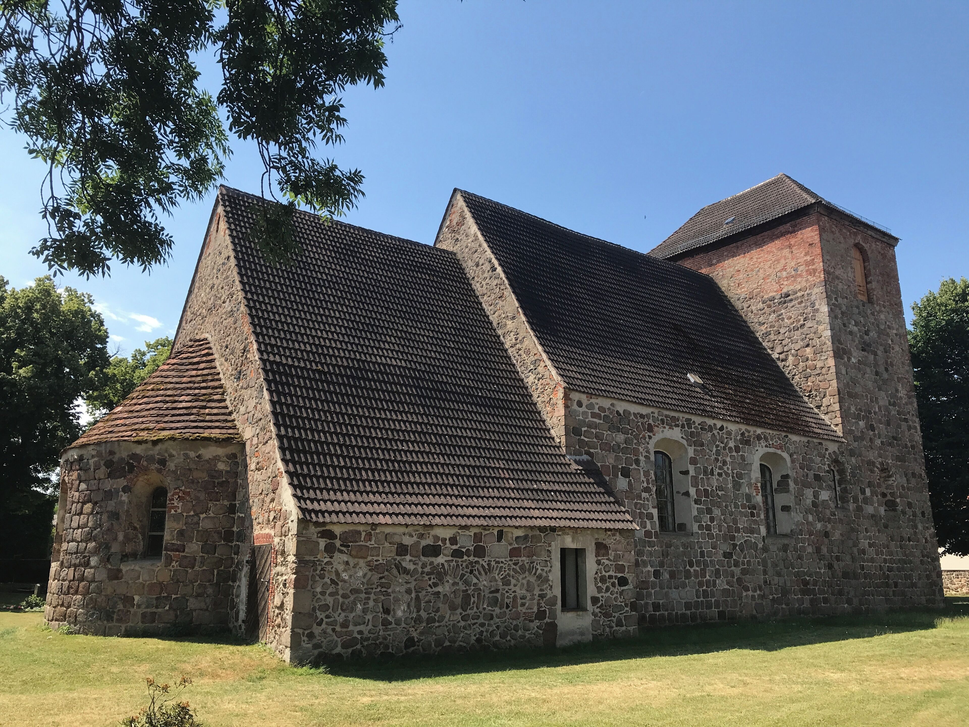 A stone church with a steeply pitched roof and a bell tower.