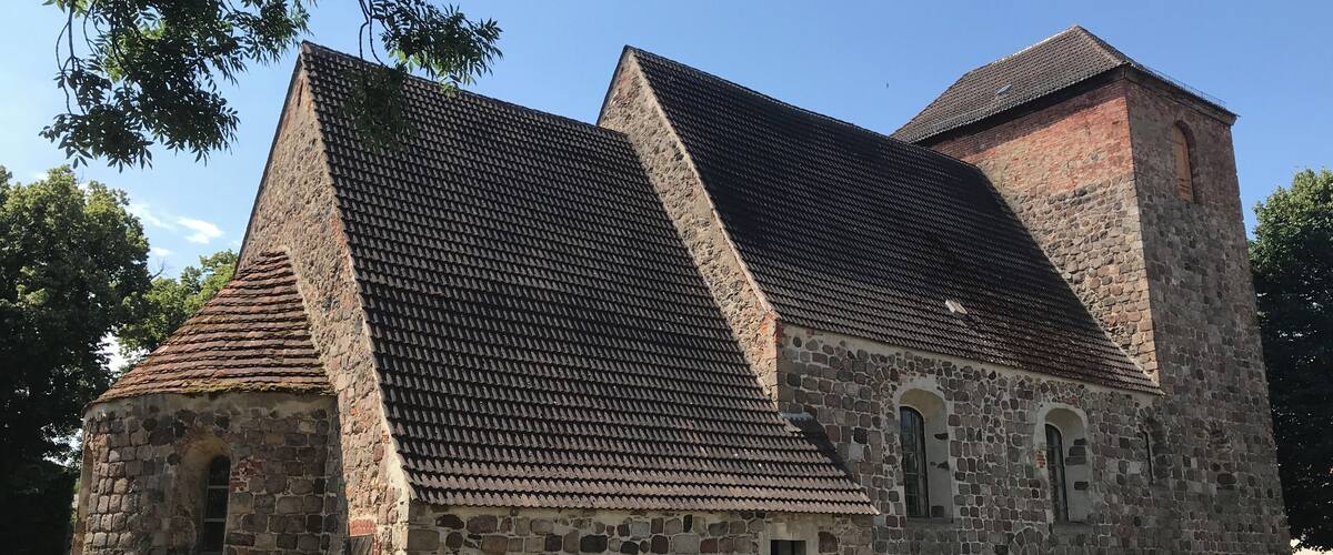 A stone church with a steeply pitched roof and a bell tower.