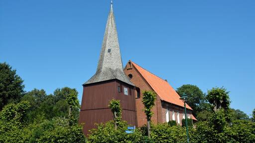 Una iglesia con un campanario alto y un techo rojo.