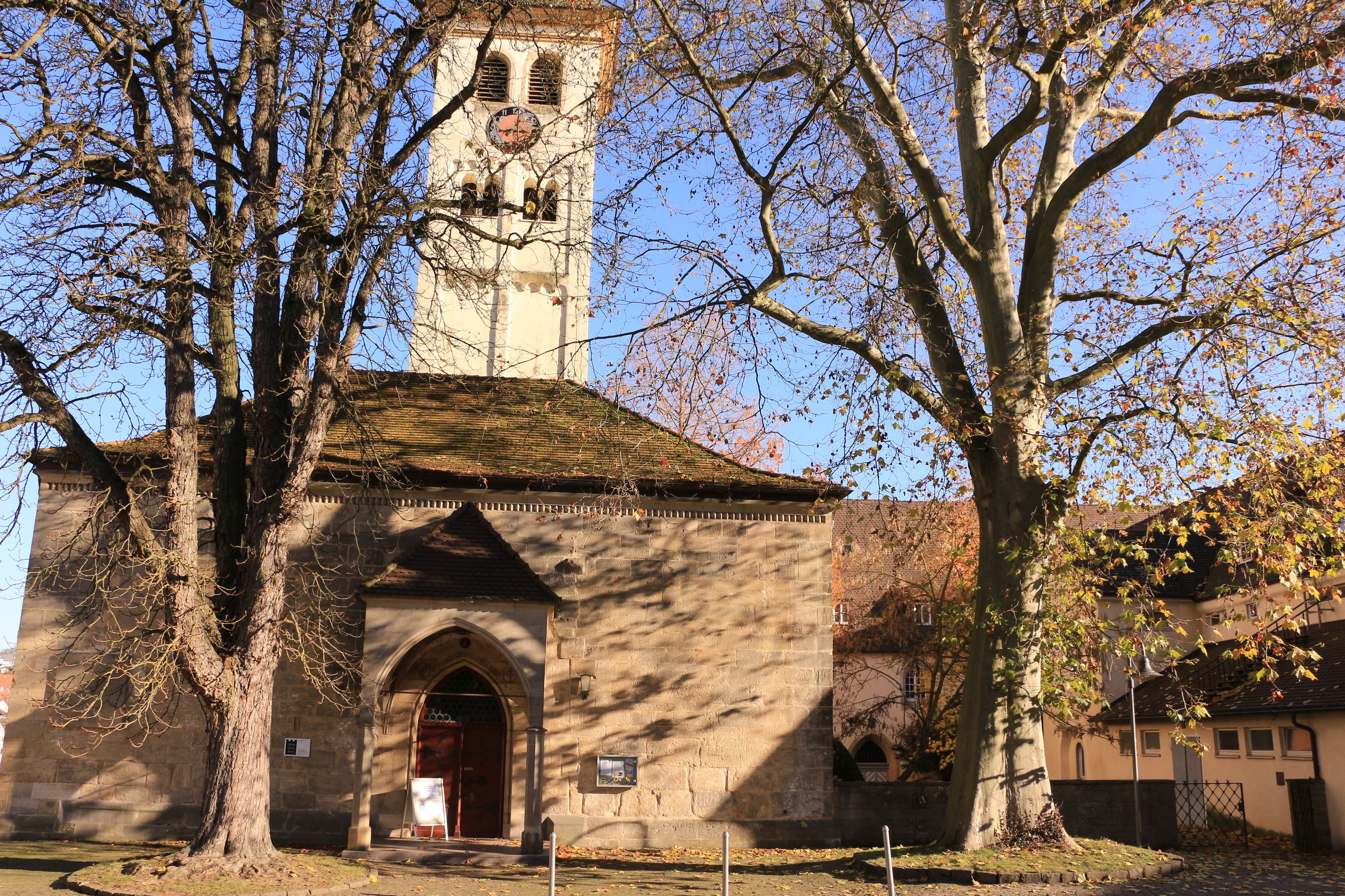 En kirke med et klokketårn, omgivet af træer med efterårsblade.