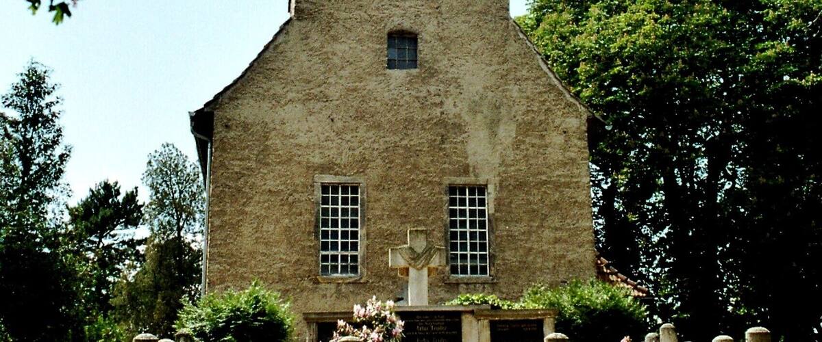 A stone tower with a conical roof, surrounded by a garden with flowers and a fence.