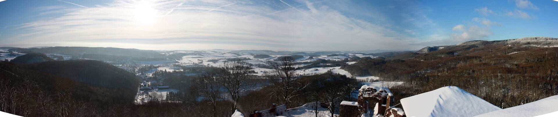 A panoramic view of a snow-covered landscape with rolling hills and a clear sky.