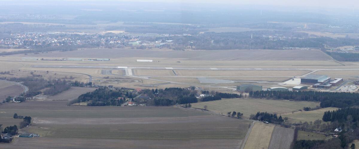 An aerial view of a rural area with fields, a small town, and a large industrial complex.