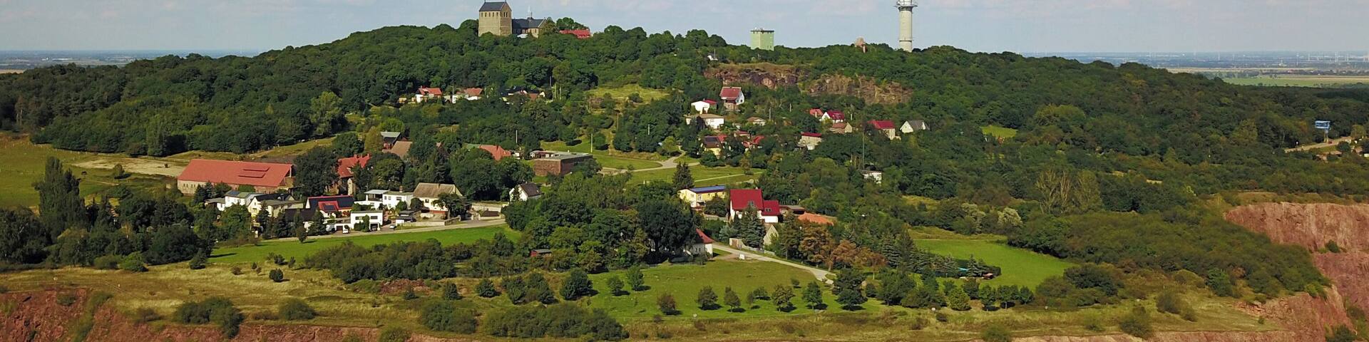A hilly landscape with a prominent tower, lush greenery, and scattered buildings.