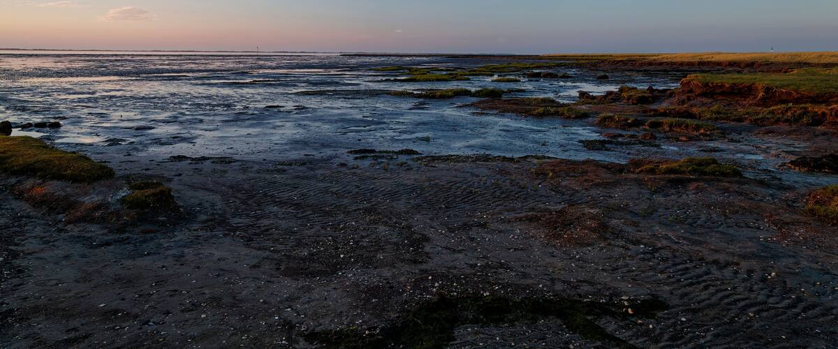 A coastal landscape with rocky terrain and a clear sky.