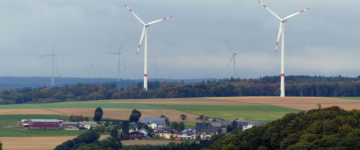 Wind turbines in a rural landscape with houses and fields.