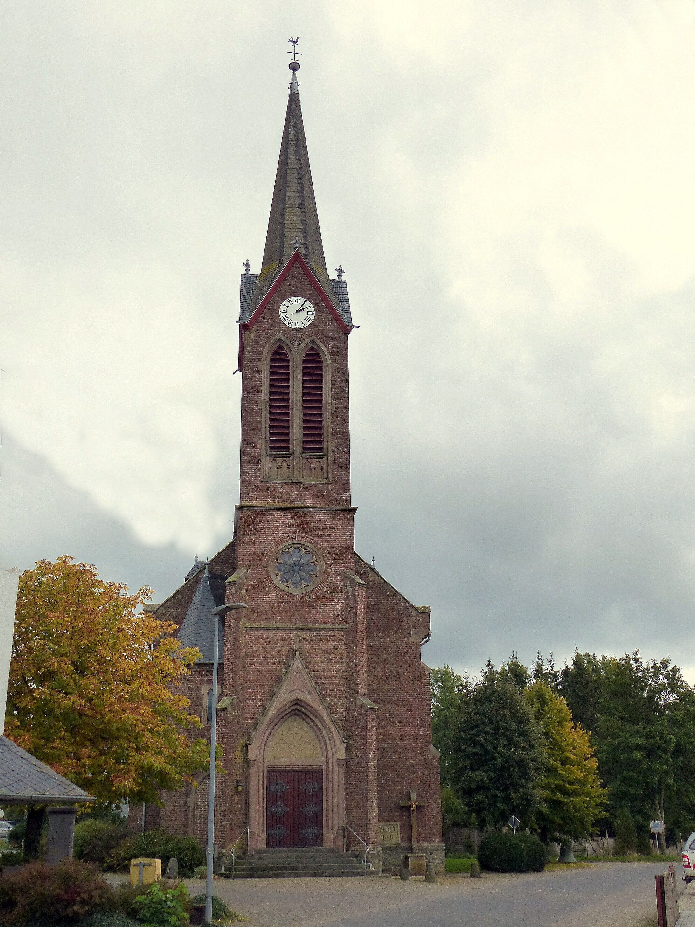 A church with a tall steeple, a clock, and a cross at the top.
