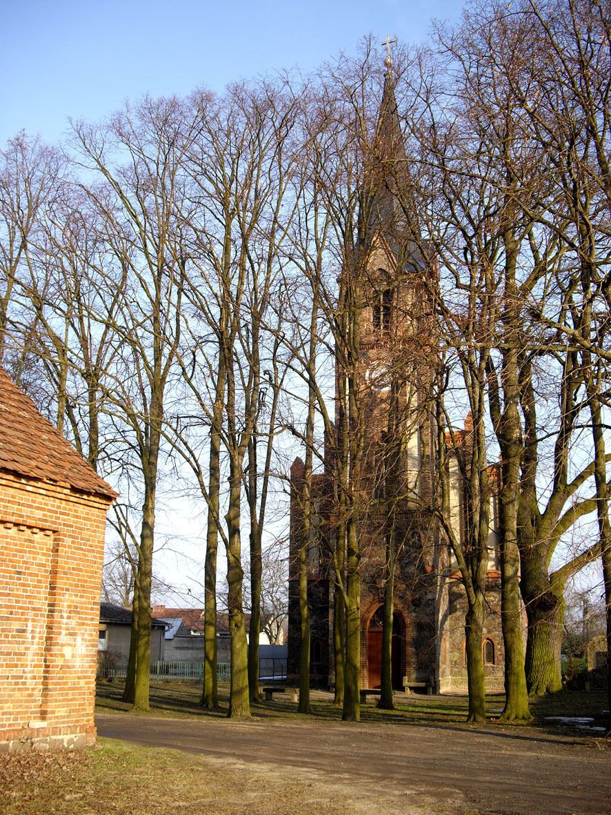 A church surrounded by leafless trees and a brick building.
