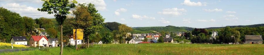 Paisagem rural com casas, uma estrada e um sinalizador indicando direções para Eppendorf e Breitenau.