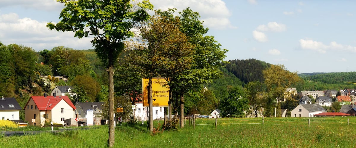 A rural landscape with houses, a road, and a signpost indicating directions to Eppendorf and Breitenau.