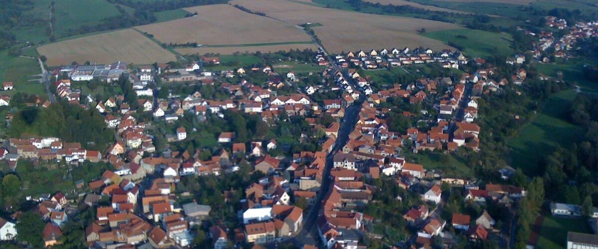 A rural village with red-roofed houses, surrounded by fields and rolling hills.
