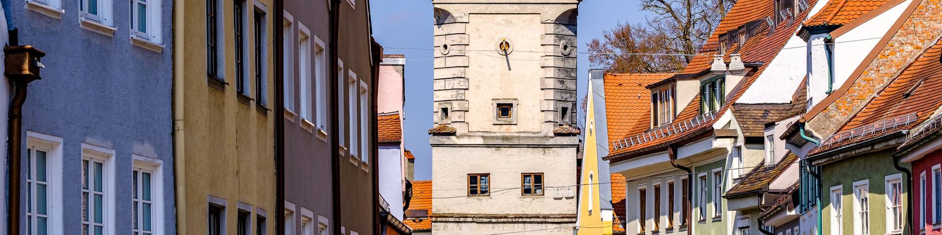 A historic tower with a conical roof amidst colorful buildings.