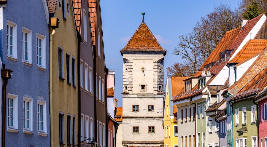 A historic tower with a conical roof amidst colorful buildings.