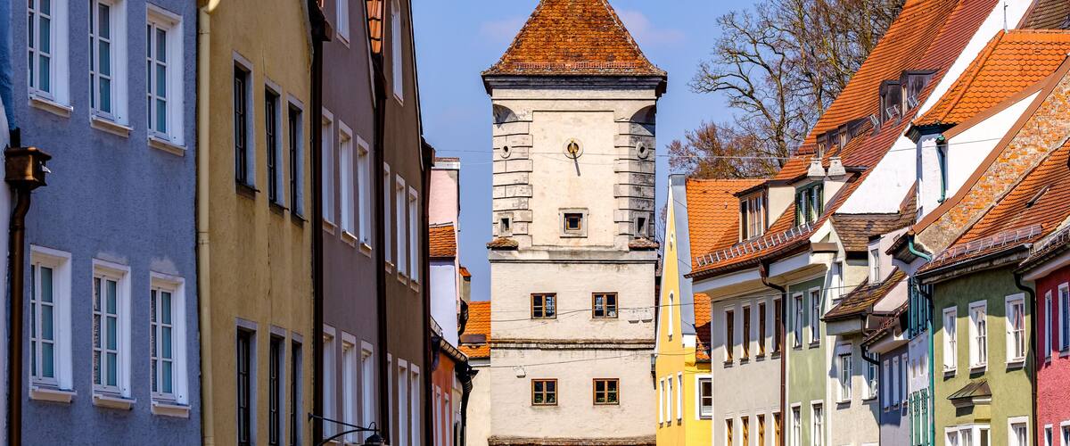 A historic tower with a conical roof amidst colorful buildings.