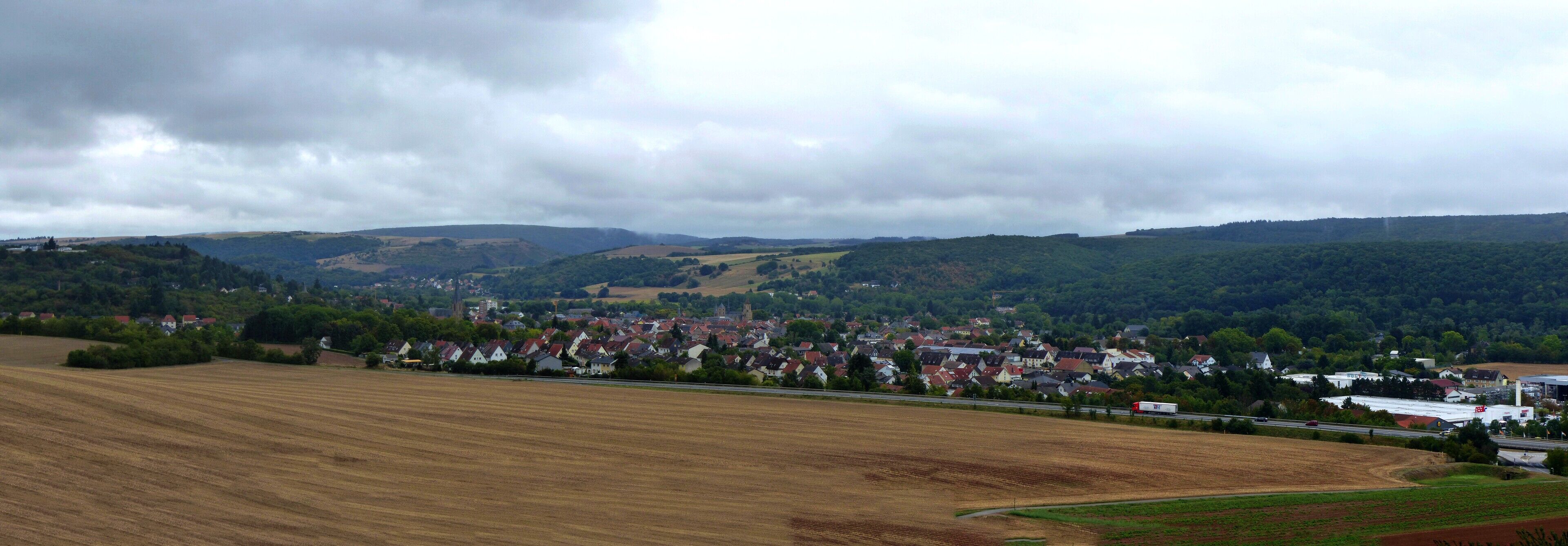 A rural landscape with fields, a small town, and rolling hills.