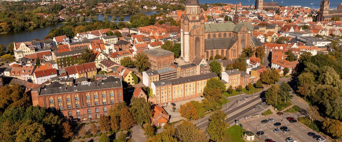 A panoramic view of a historic town with a prominent church, a river, and a distant coastline.