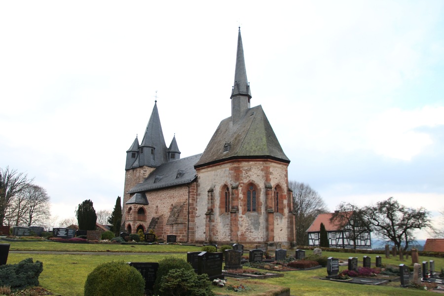 A historic church with a tall spire and multiple smaller towers, surrounded by a cemetery with headstones.