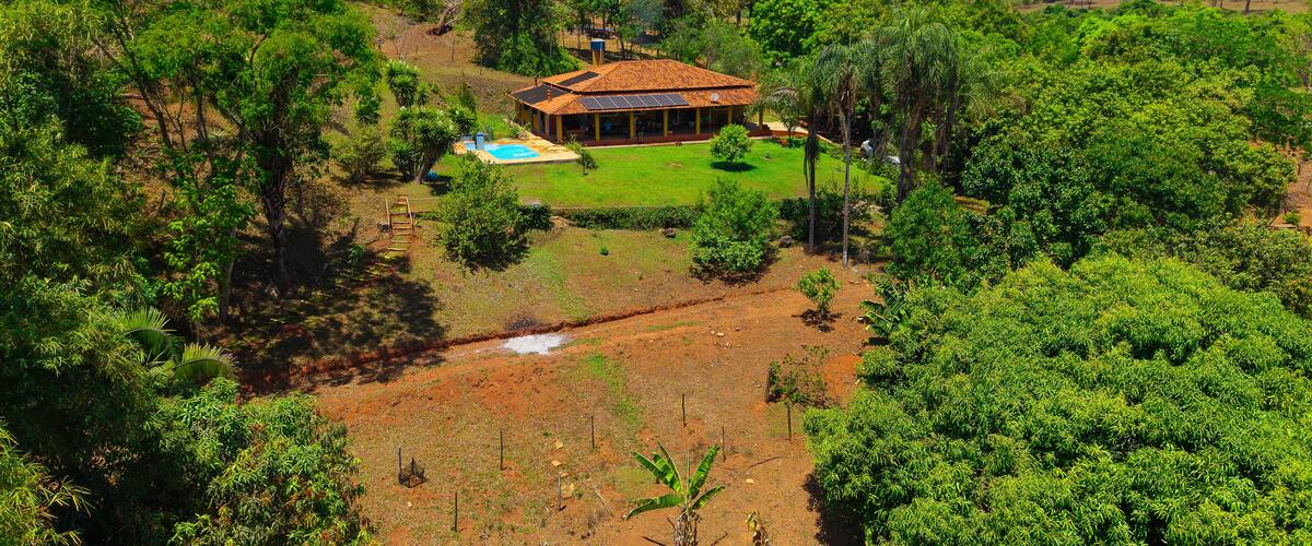 A house surrounded by lush greenery and a swimming pool.