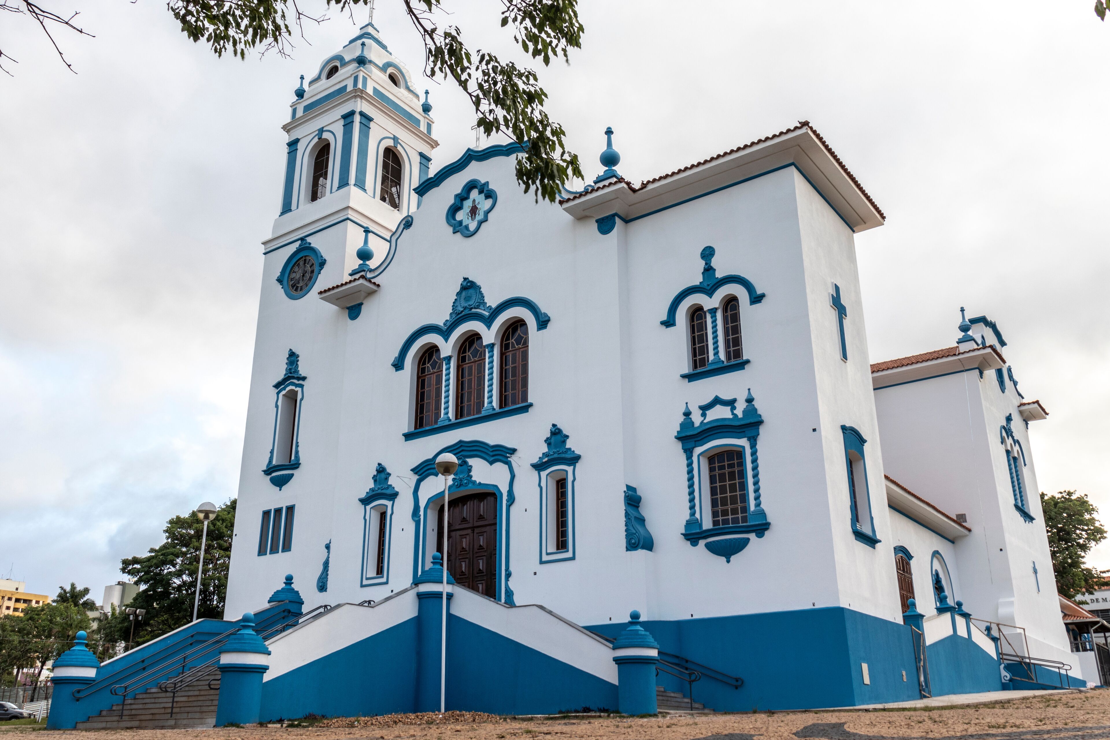 A white and blue church with a bell tower and a cross.