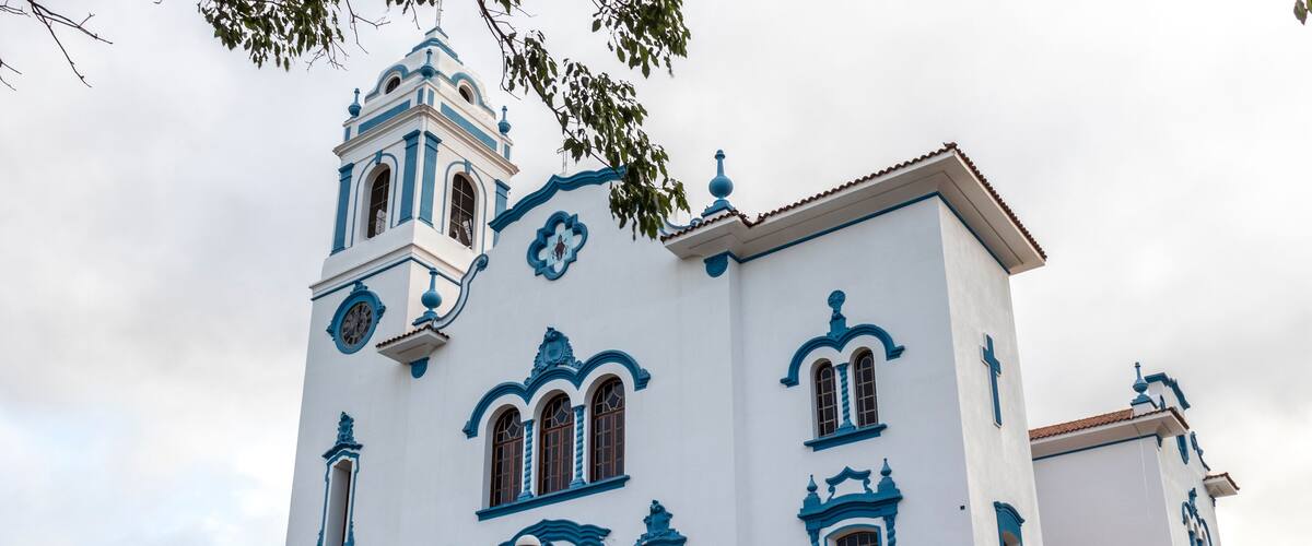 A white and blue church with a bell tower and a cross.