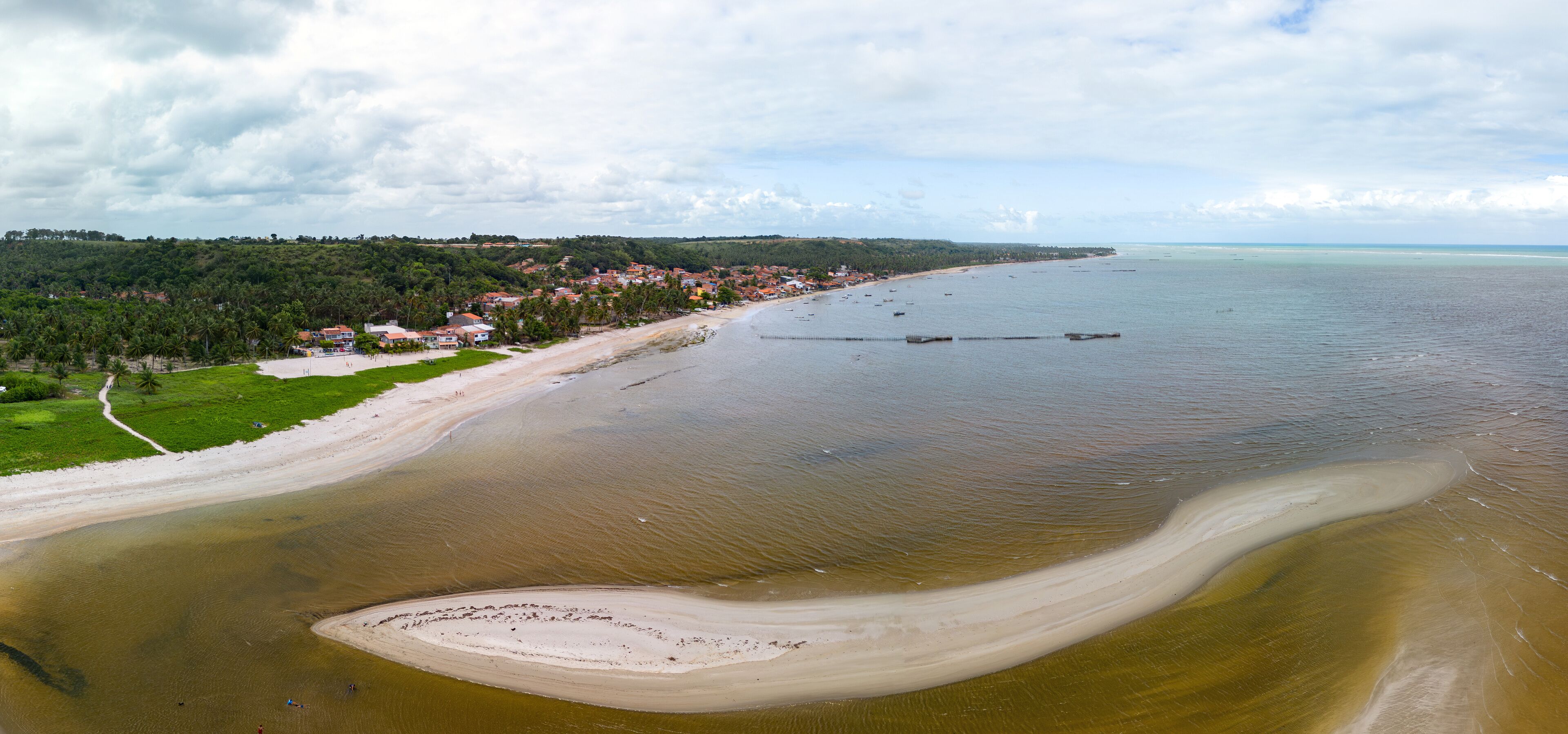 A coastal landscape with a beach, a small island, and a town in the background.