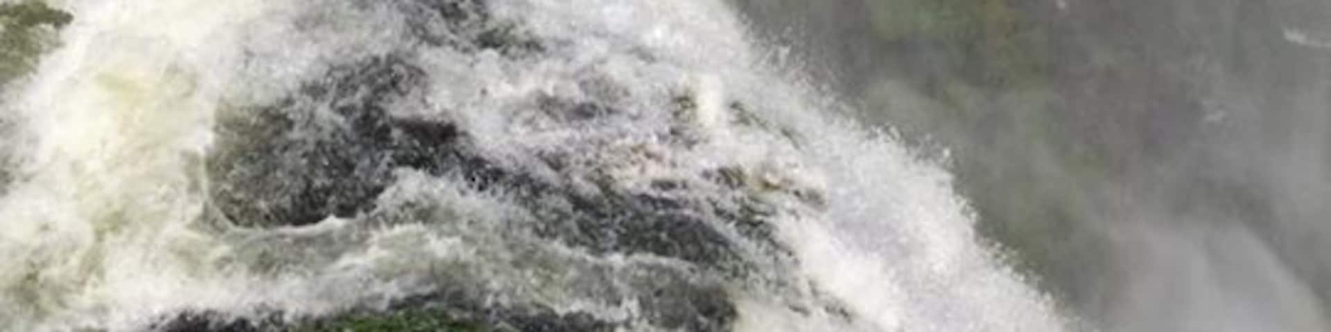 A large waterfall with a rainbow, surrounded by lush greenery.