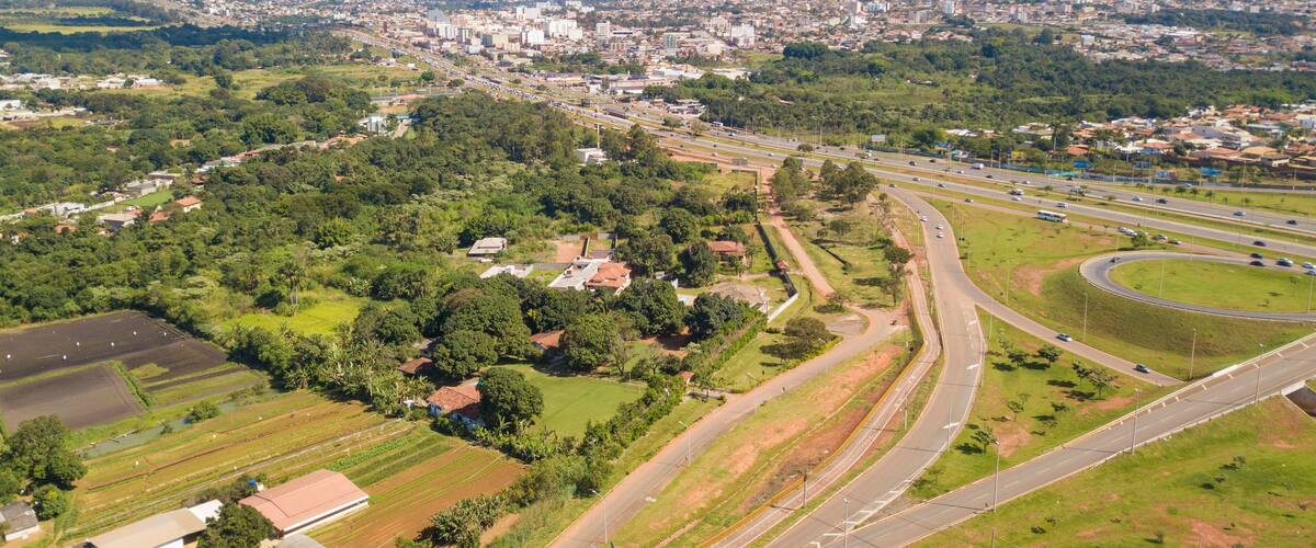 An aerial view of a city with a highway, green fields, and residential areas.
