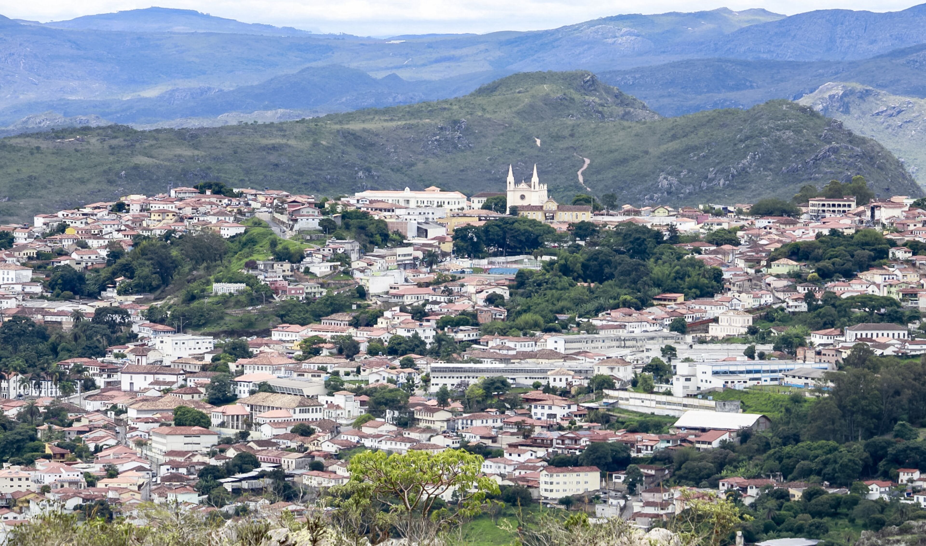 A hillside town with dense housing, a prominent church with twin spires, and rolling hills in the background.