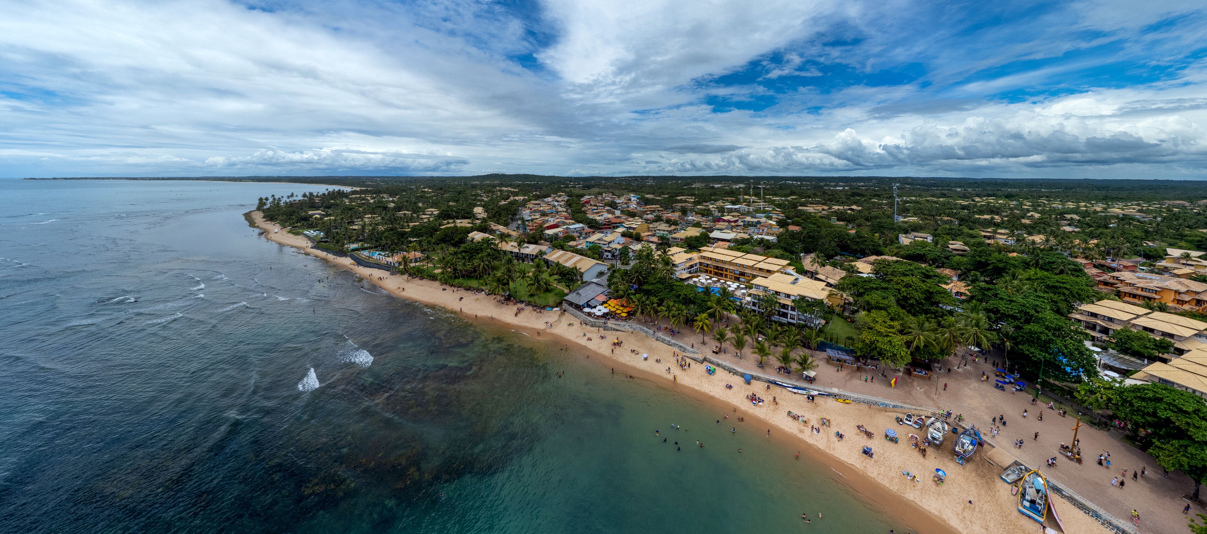 A coastal town with a beach, buildings, and palm trees.